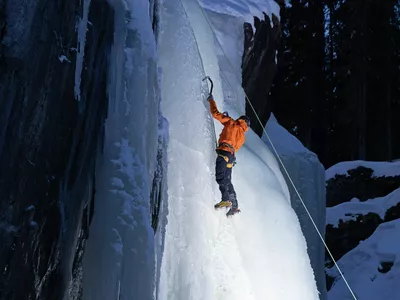 En mann i oransje jakke klatrer is i Hemsedal.