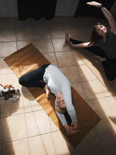 Yoga på et badegulv med en hund som ser på.