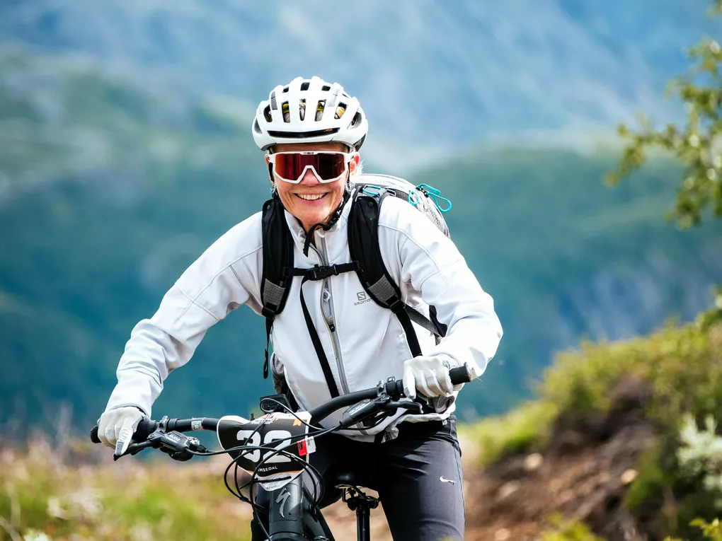 Jente som sykler på mtb på en sti på fjellet i Hemsedal. Hun har solbriller og hjelm.