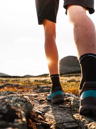 Mann som går på fjelltur under solnedgangen