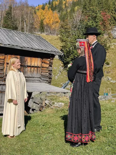 Mennesker på gårdstun. Natur og gammel bygning i bakgrunn