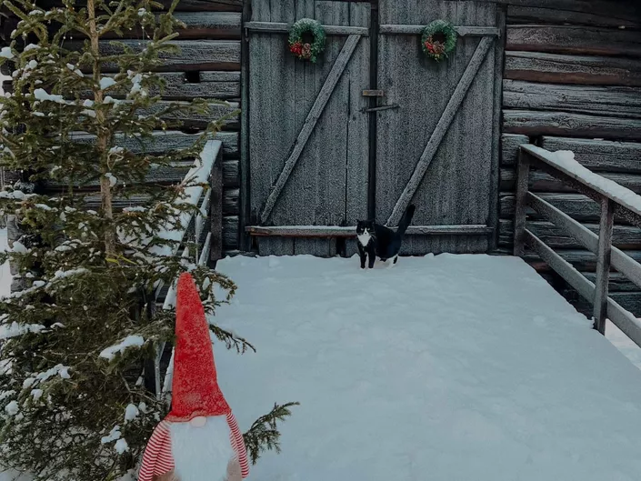 Bilde av en låve med et tre og en liten nisse på vinteren