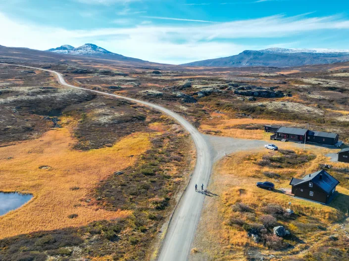 Flævasshytta uten snø, to personer som sykler innover i fjellet. Bilde er tatt ovenfra og ned.
