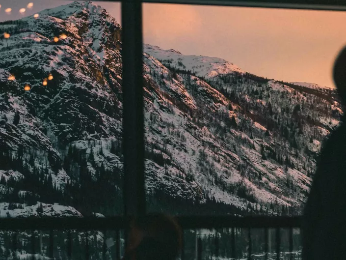 Person ser på solnedgang i vinterfjell