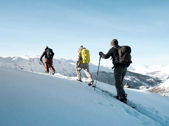 Tre personer som går topptur i fjellet, i bakgrunnen er solheisen.