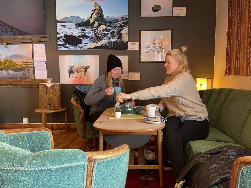 To damer som sitter ned og koser seg med kvikaku og kaffe.