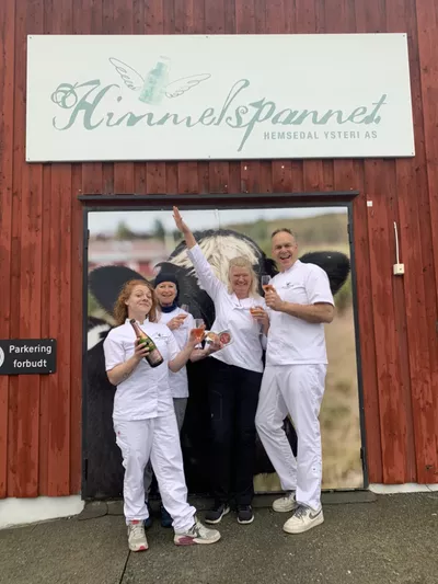 Mennesker som smiler til kamera, foran inngangen på himmelspannet