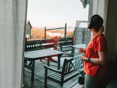 Kvine står til høyre for bilde og ser ut av vinduet med svarte hodetelefoner