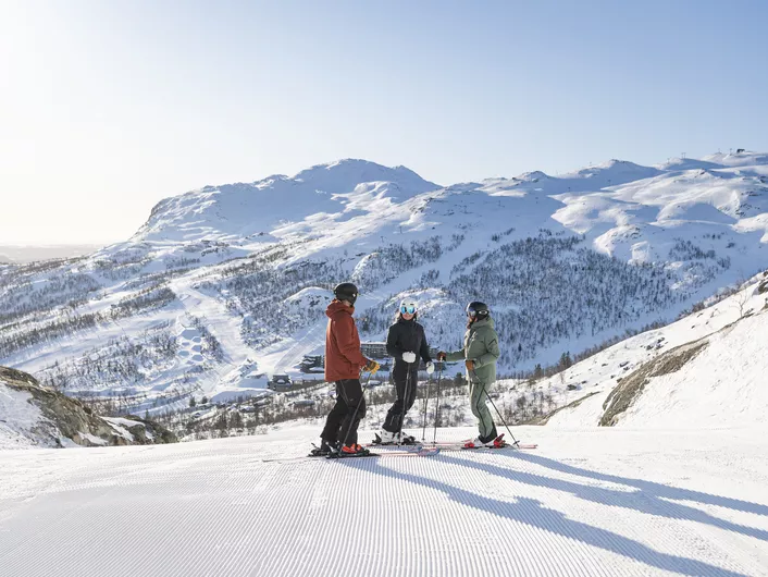 Tre personer står med ski på i skiløypa i SkiStar Hemsedal