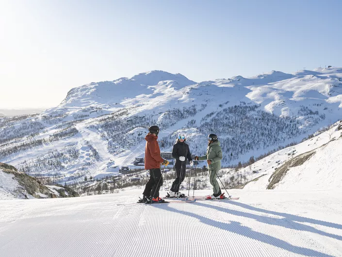Tre personer står med ski på i skiløypa i SkiStar Hemsedal