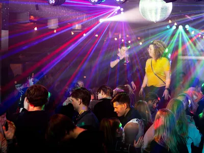 Lilla og blått lys, på afterskien, flere mennesker og en dame med gul t-skjorte.