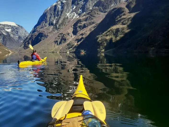 To som padler kajakk i en fjord.