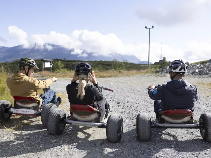 Tre personer som sitter på hver sin mountain cart.
