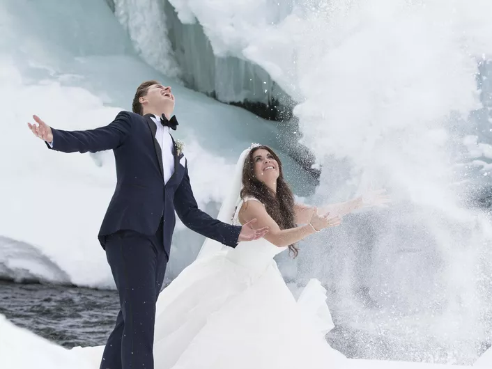 Mann og dame som akkurat har giftet seg, og kaster snø opp i luften.