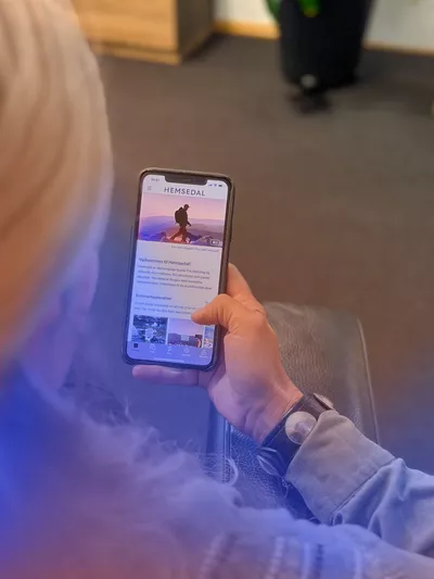 Dame som sitter å leser på startsiden av Hemsedal appen