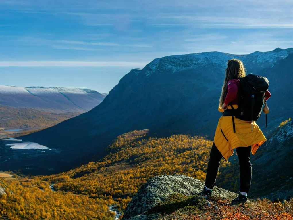 Kvinne med sekk på ryggen skuer utover fjell-landskap i Hemsedal