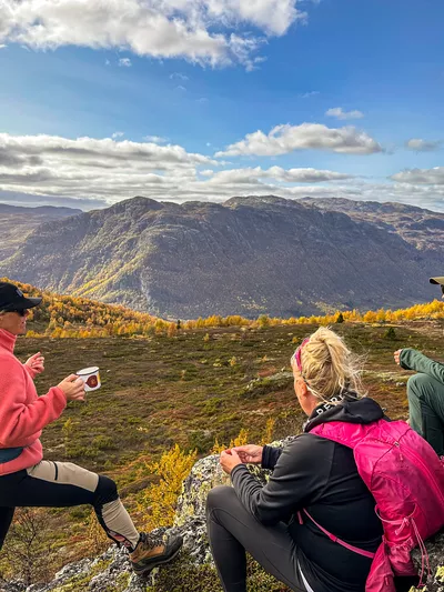 Tre mennesker tar seg en pause ved varde på fjellet i Hemsedal