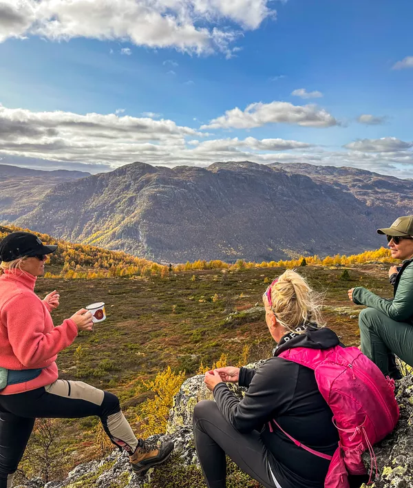 Tre mennesker tar seg en pause ved varde på fjellet i Hemsedal