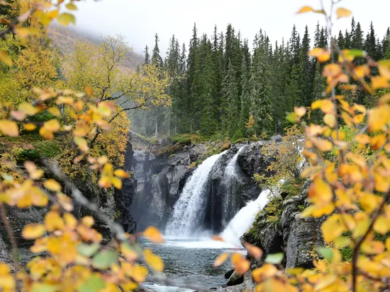 Rjukandefossen fra avstand med gule trær på hver side