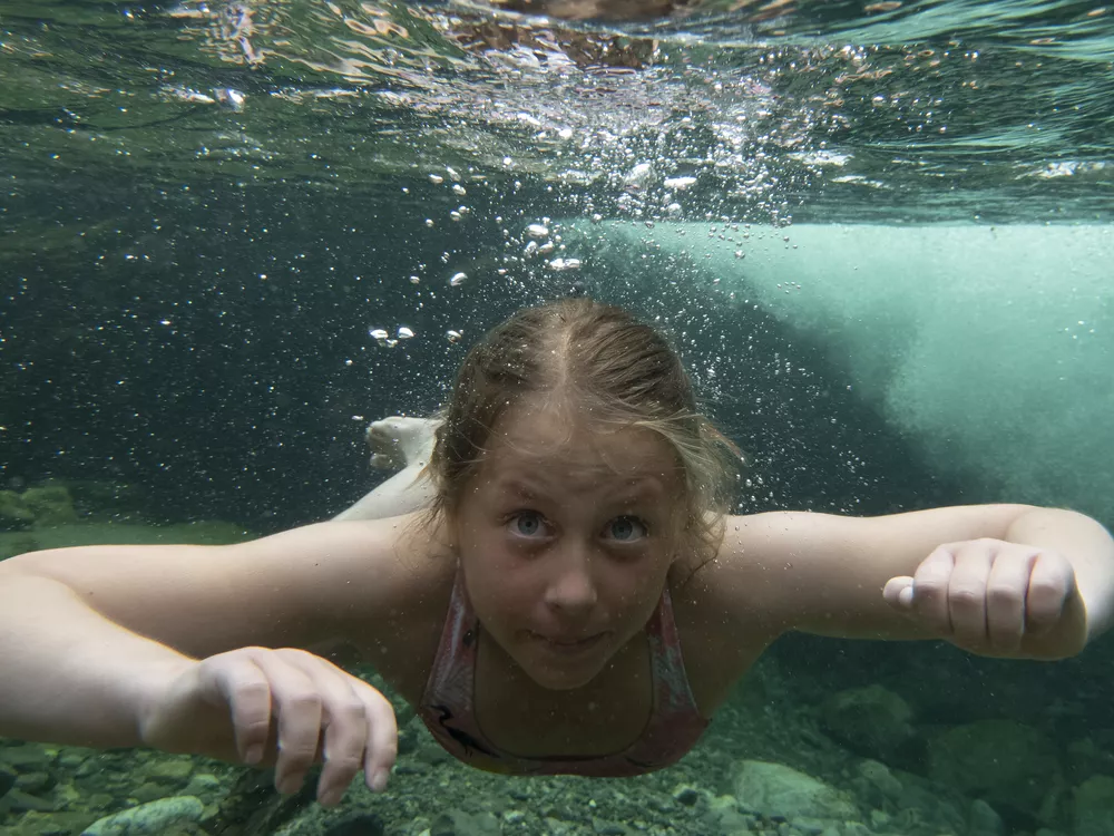 Jente som svømmer under vann.