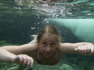 Jente som svømmer under vann.