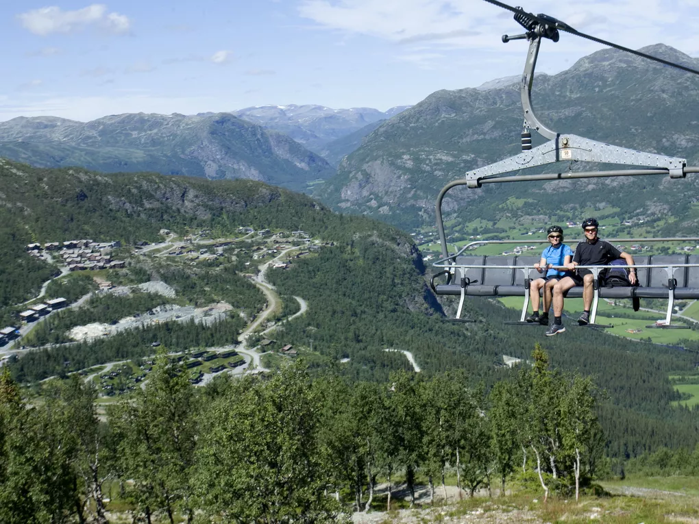 Mann og dame som sitter i heisen opp for å sykle.