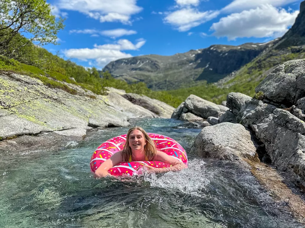 Dame som bader i donut i elva (sommer) og ser mot kameraet.