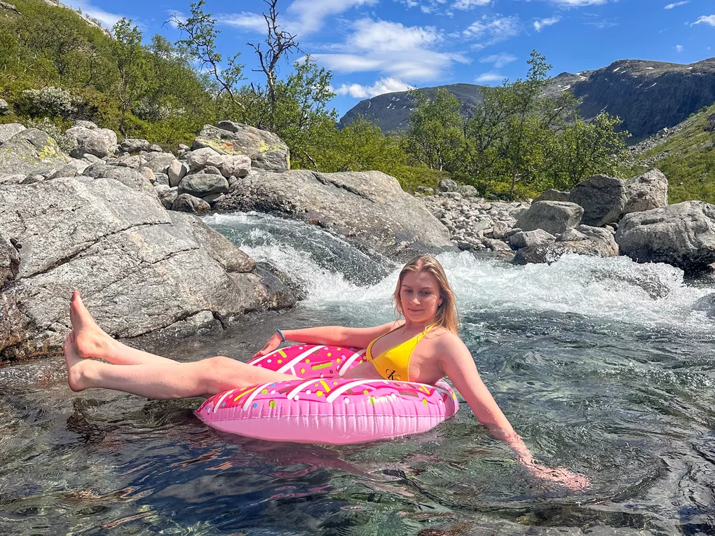 Dame som sitter i en donut i elva (sommer).