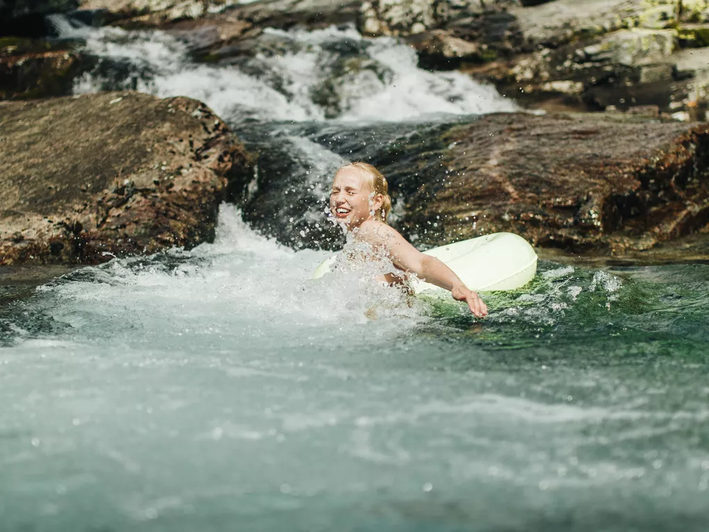 Jente som bader i elva, med badeleke.