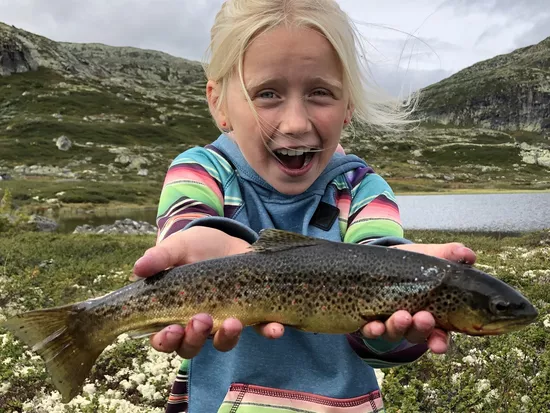 Jente/Ebba Underland som står med en fisk i hånden