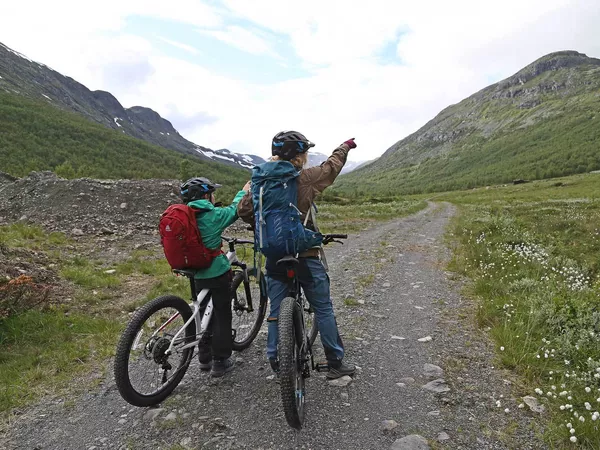 To mennesker som peker opp på fjellet foran dem