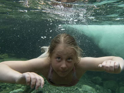 Jente som svømmer under vann.