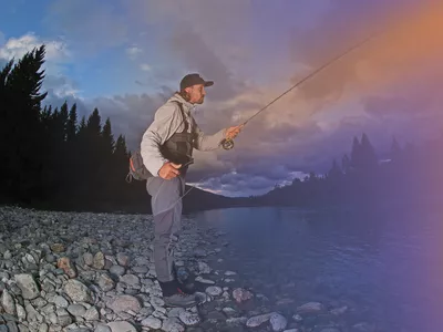 En mann som står og fisker i elva.