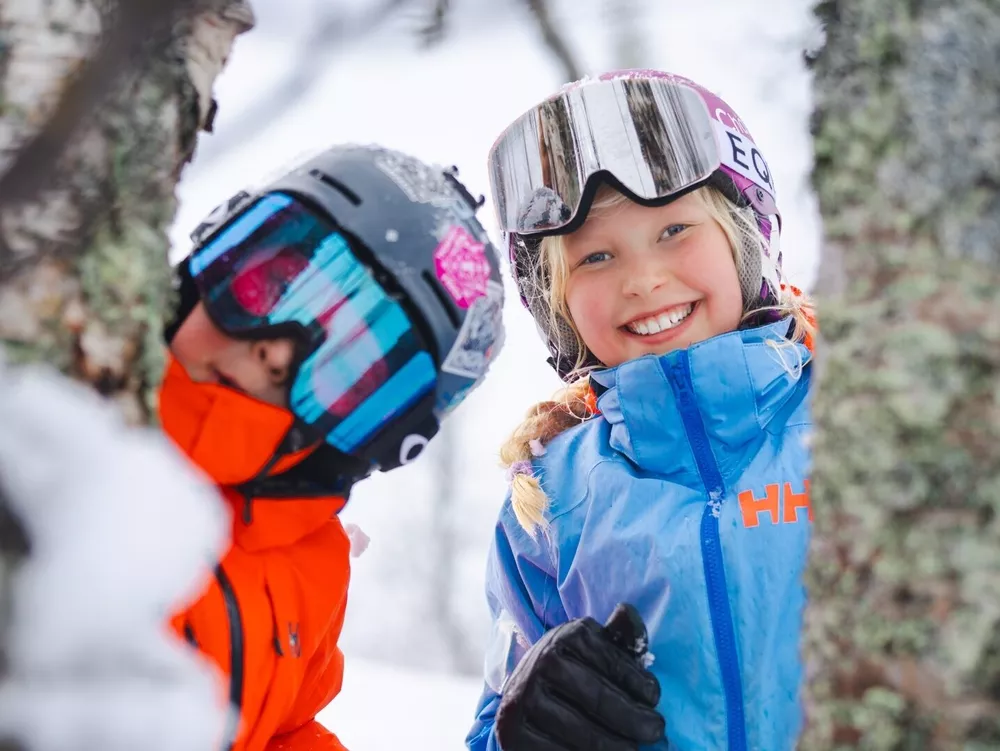 Friends skiing in Hemsedal ski resort, looking out from behind a tree